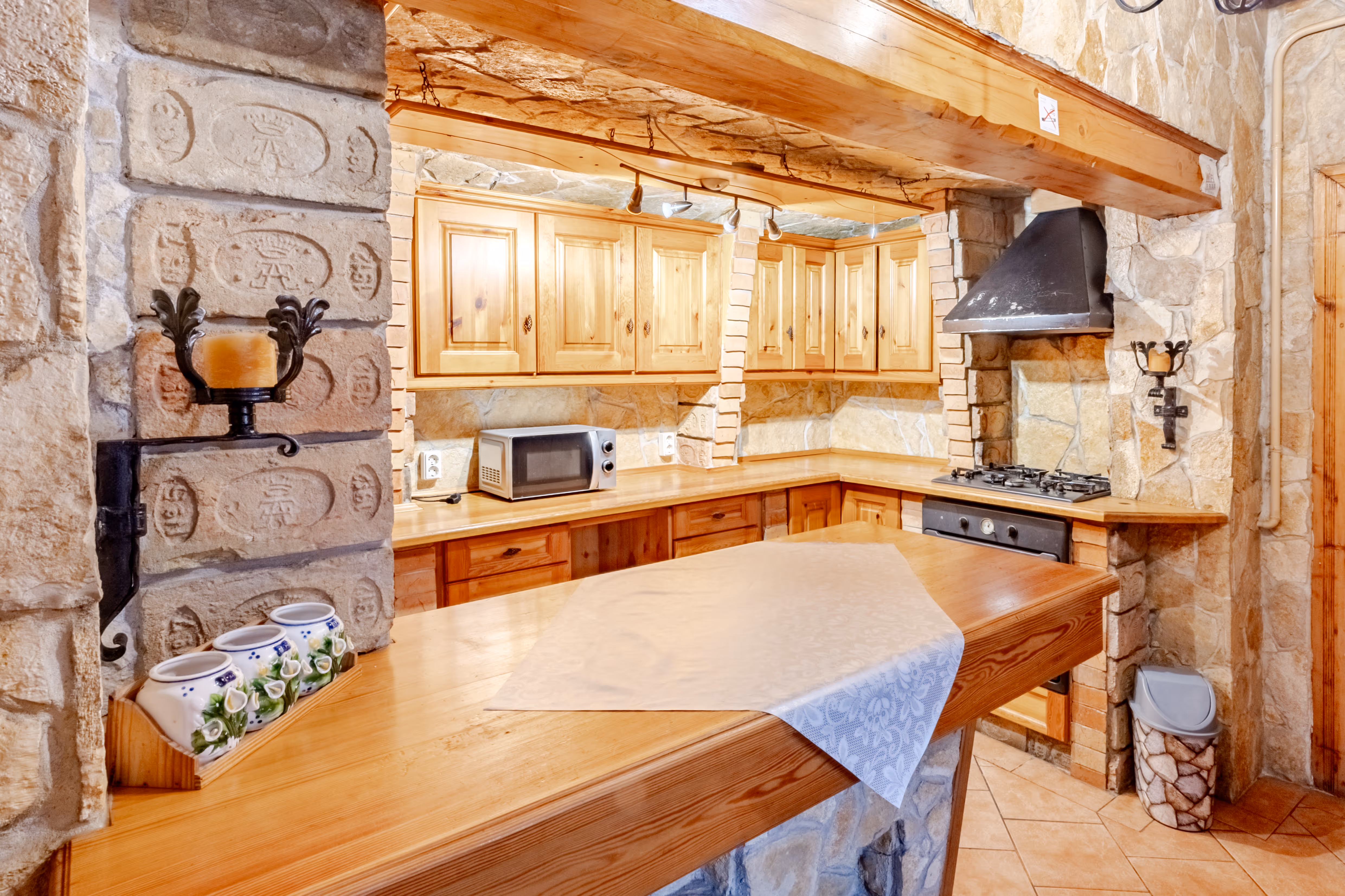 Rusztikus konyha kőburkolatos falakkal, fa szekrényekkel és étkezőpulttal